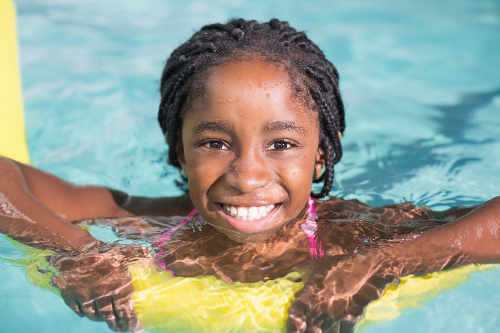 girl swimming with yellow pool noodle